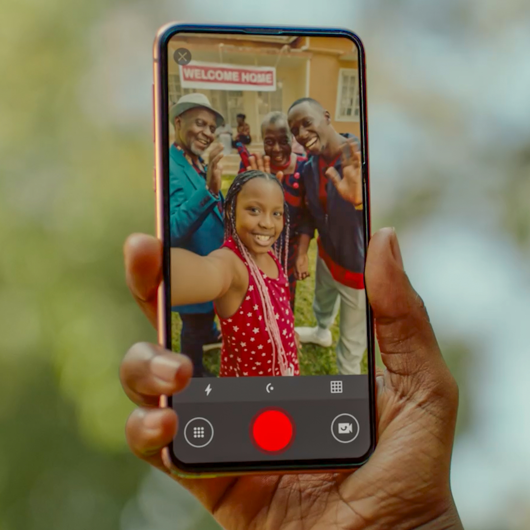 Young girl using mobile phone to photograph her family