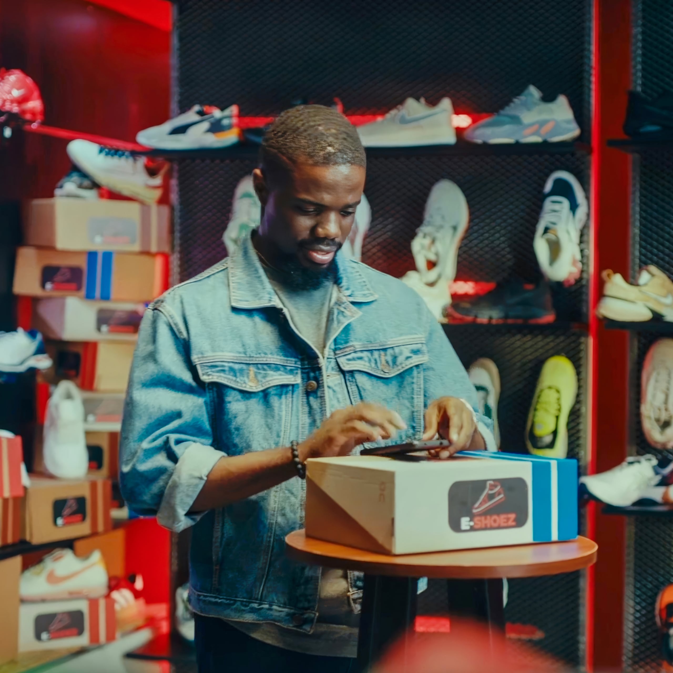 Man looking at his phone while resting it on a box of shoes