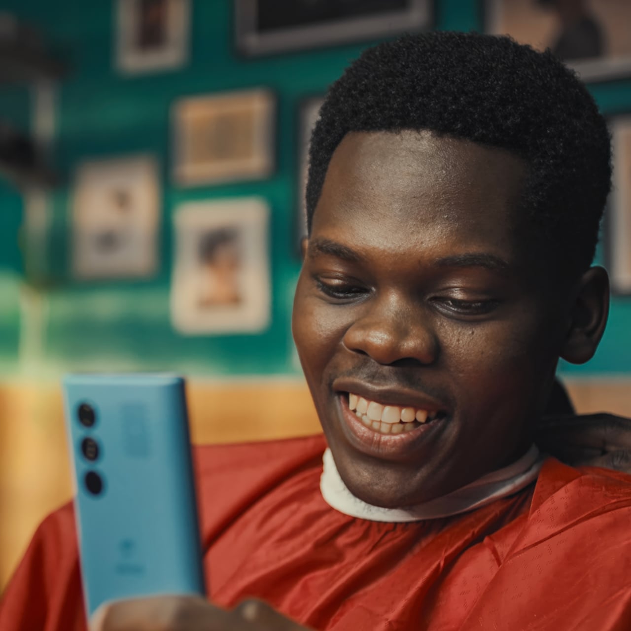Man smiling while looking at his phone in a barber shop
