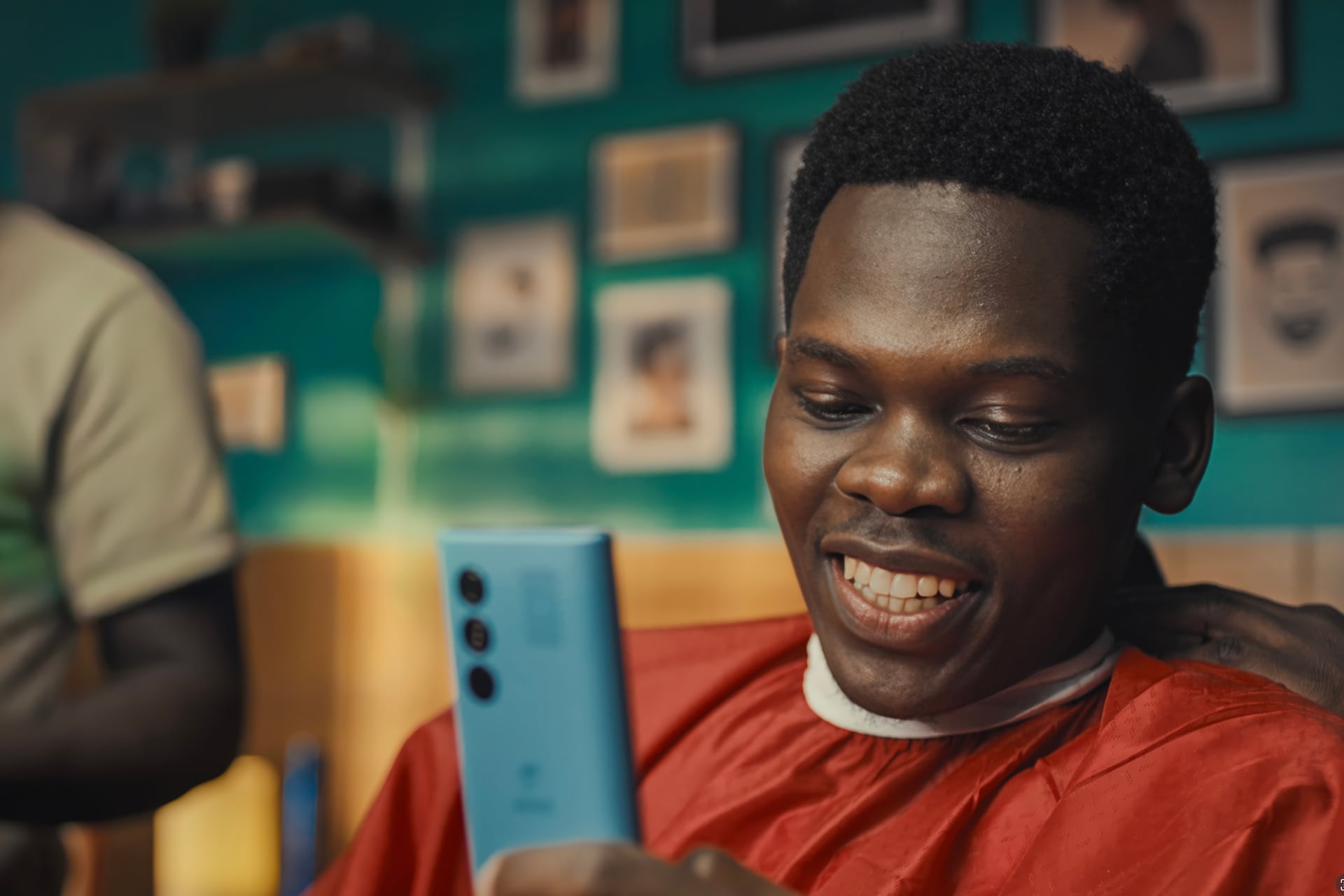 Man smiling while looking at his phone in a barber shop