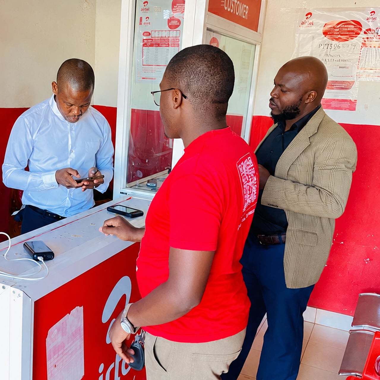 Two men and and a shopkeeper inside an airtel africa shop