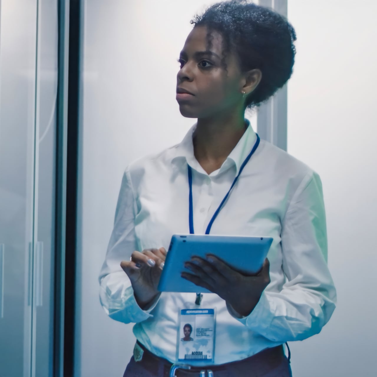 Woman with a lanyard dressed in business attire and holding a tablet