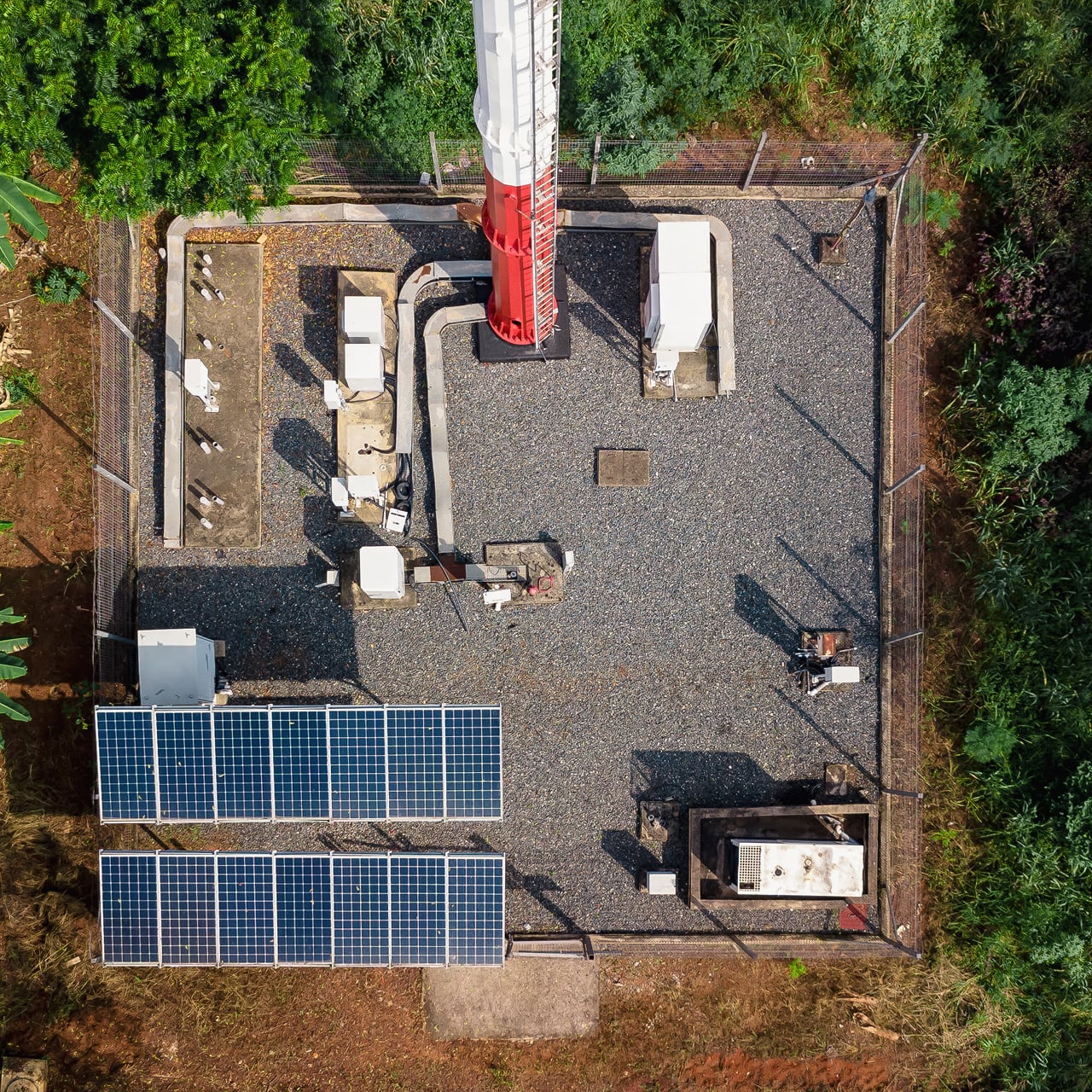 View down onto the base of an aerial tower next to which solar panels are installed