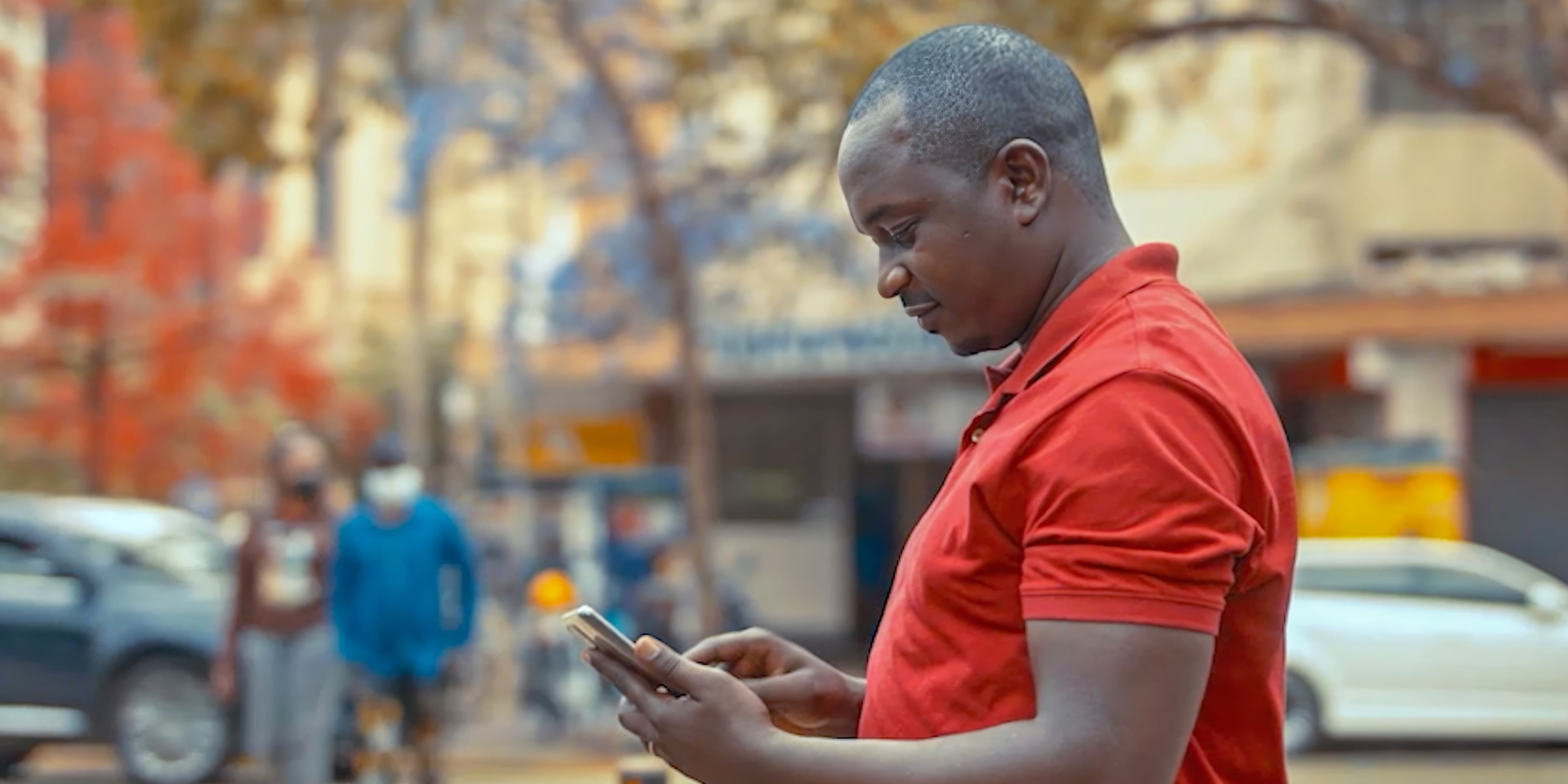 Profile of a man in the street looking at his phone