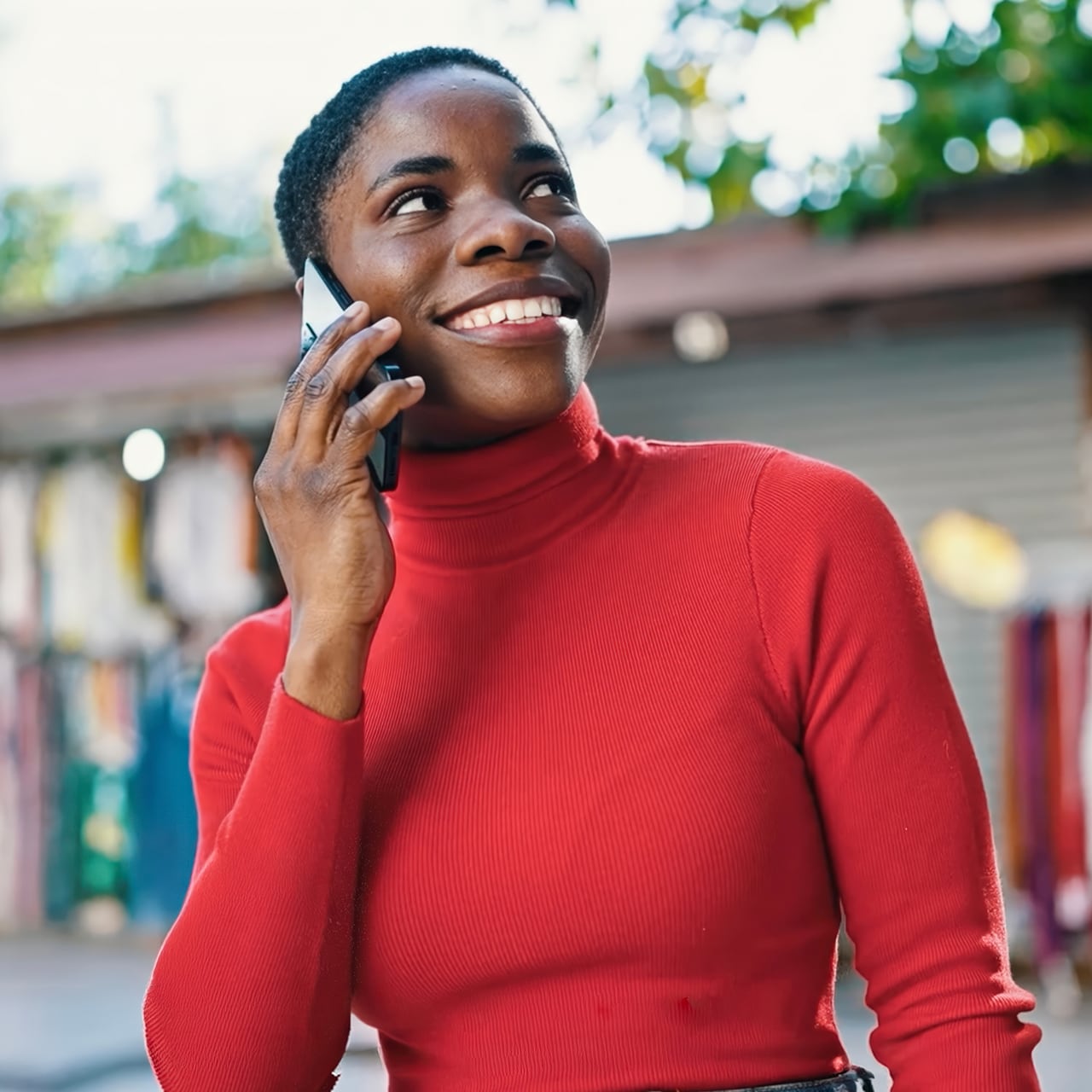 Woman in a red jumper smiling while on her phone