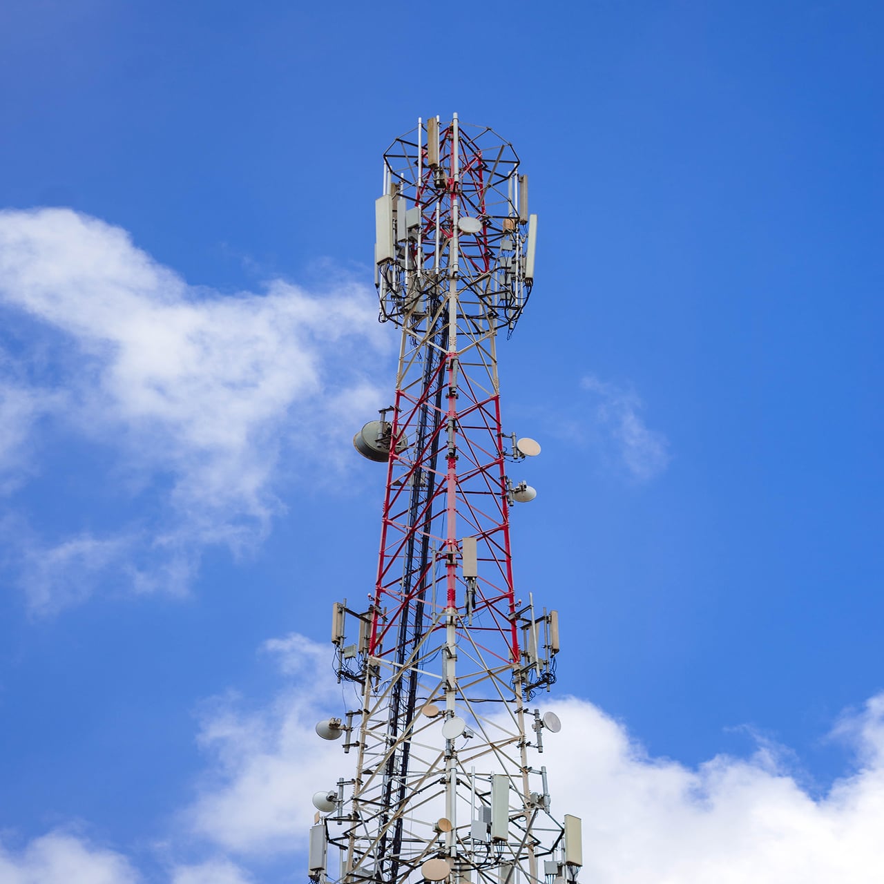 Cell tower in front of a blue sky with wisps of clouds