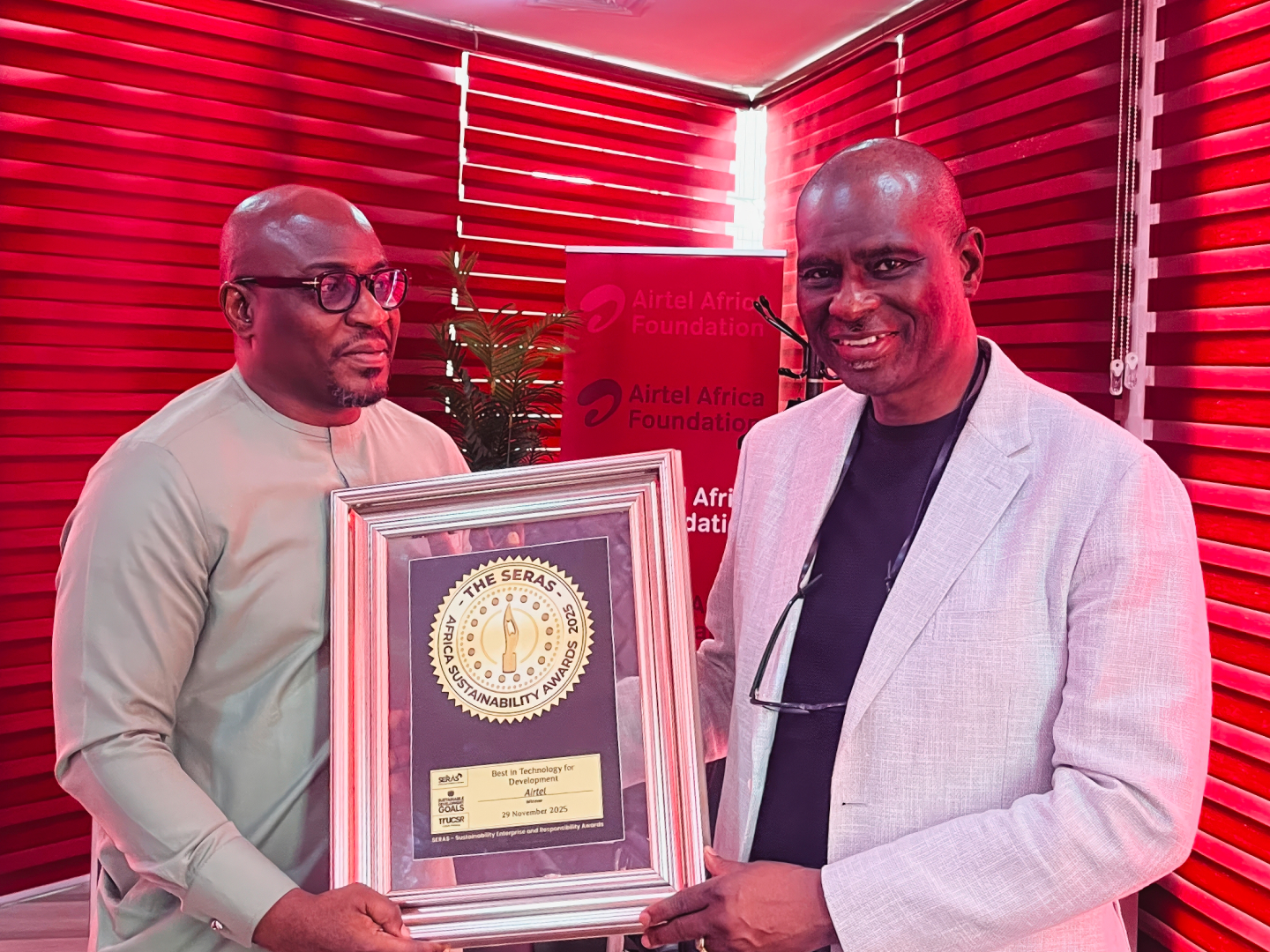 Two men posing with the framed SERAS award