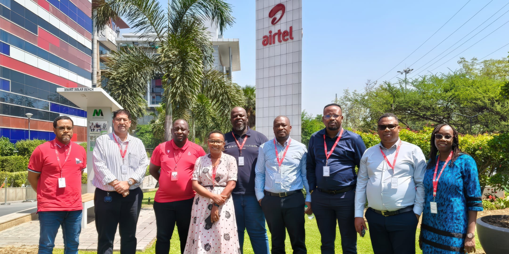A group of men and women wearing lanyards and posing in front of an Airtel sign