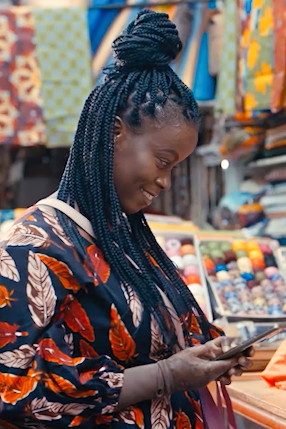 Woman in a fabric shop smiling while looking down at her phone