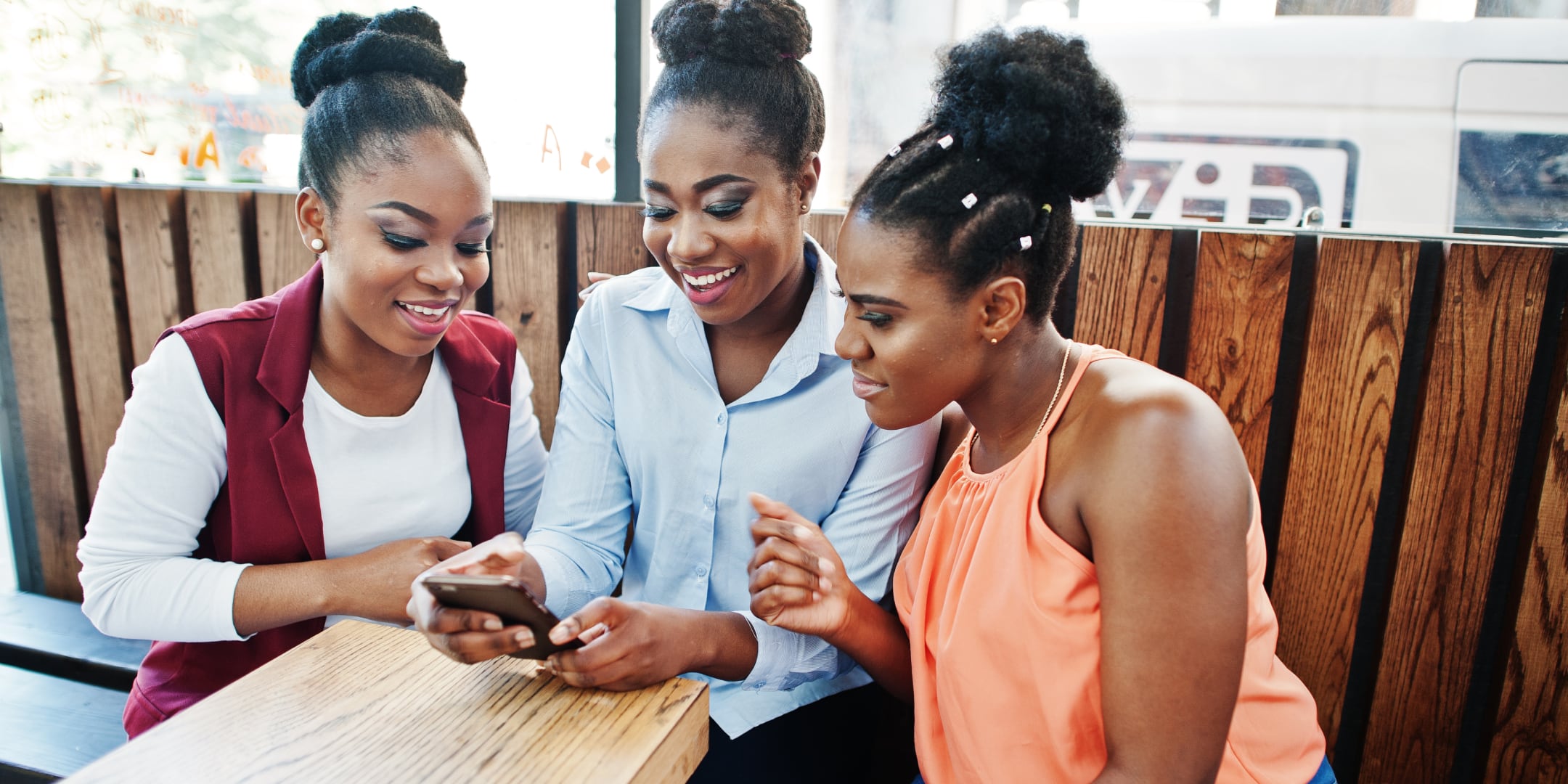 Three women gathered around a mobile phone