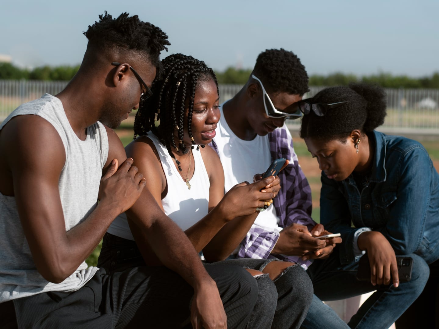 Young adults hanging out outside while engaging with their phones and each other