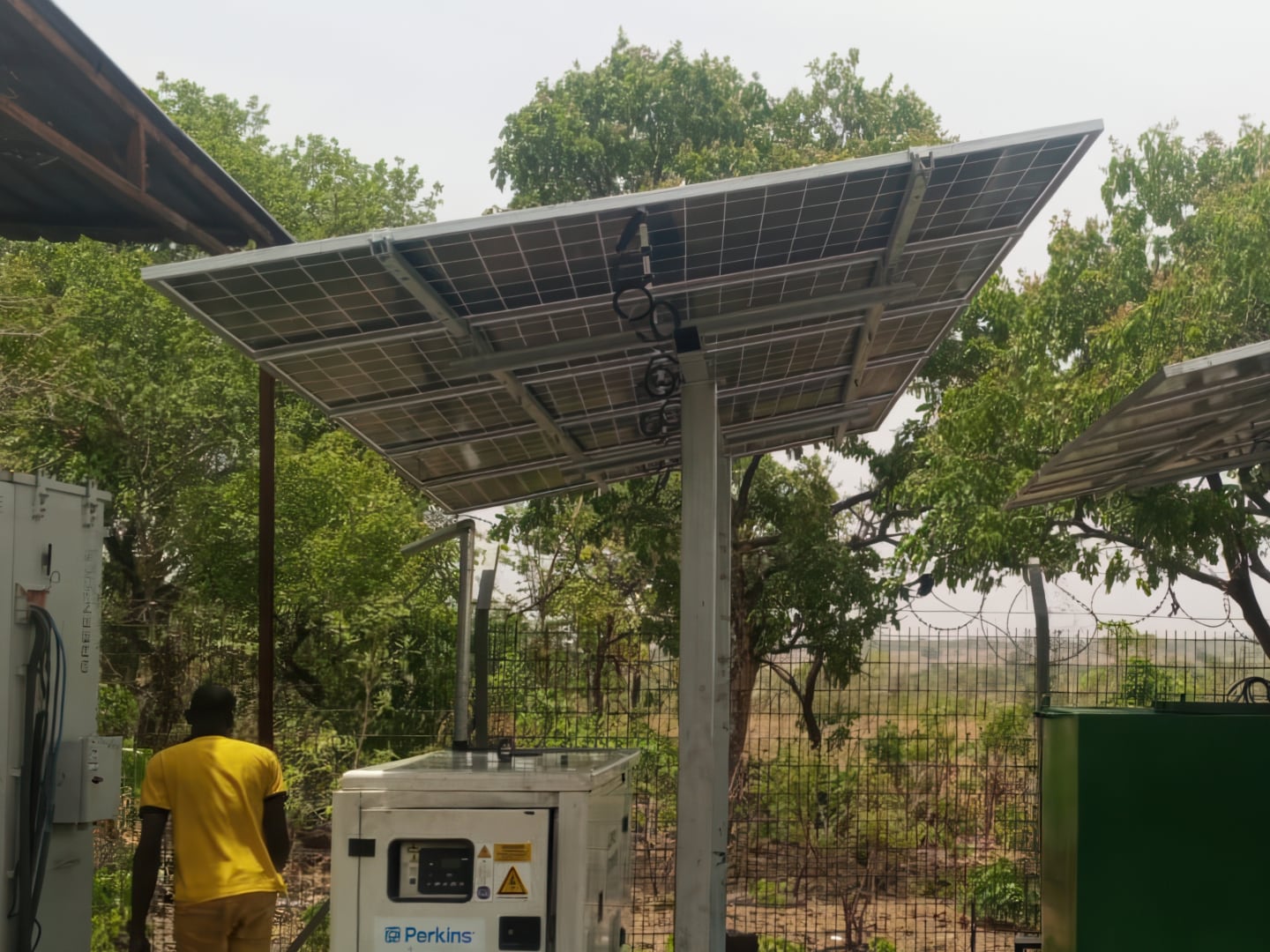 Large solar panels mounted on high metal rods with a man walking underneath them