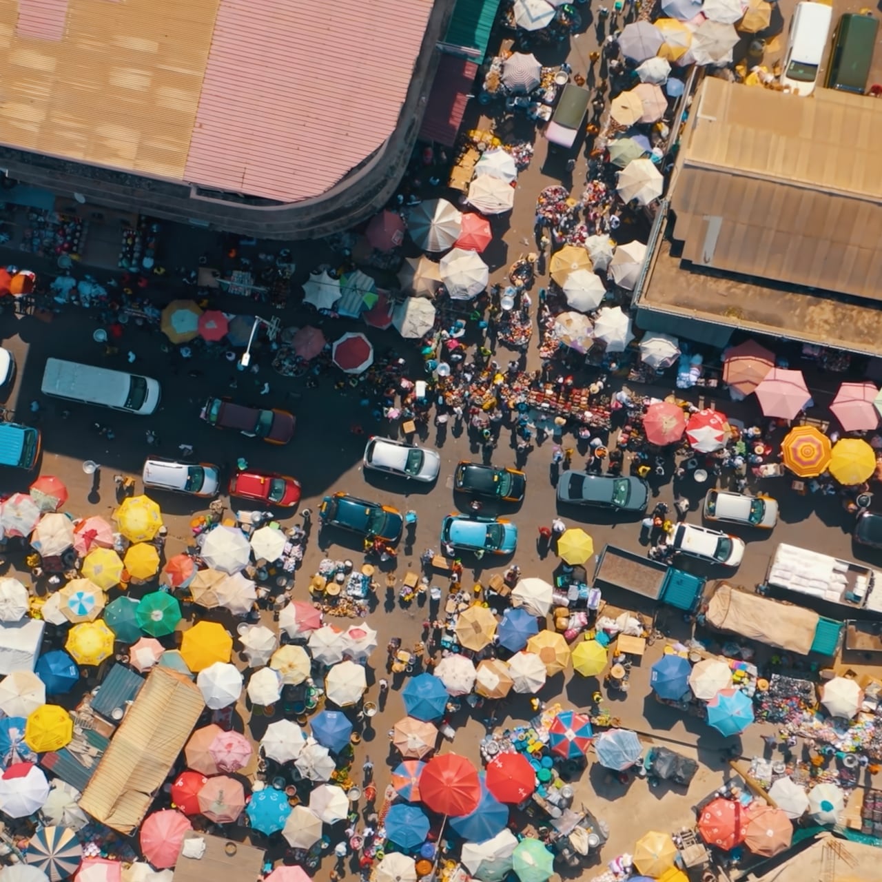 Aerial photo of vibrant bustling market place with bright colourful parasols.