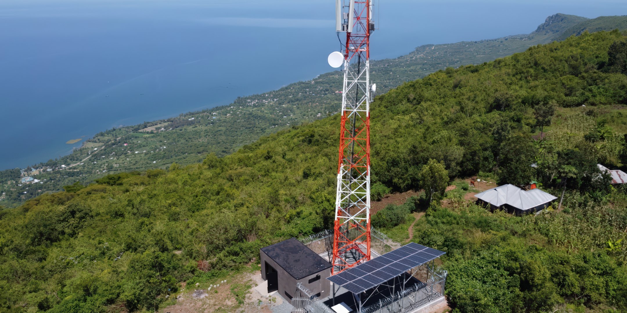 View down onto the base of an aerial tower near the ocean next to which solar panels are installed