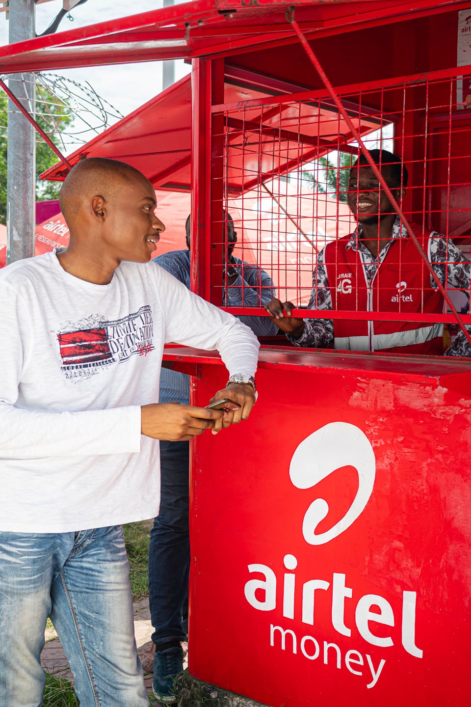A young man talking to shop keeper at an Airtel Africa kiosk