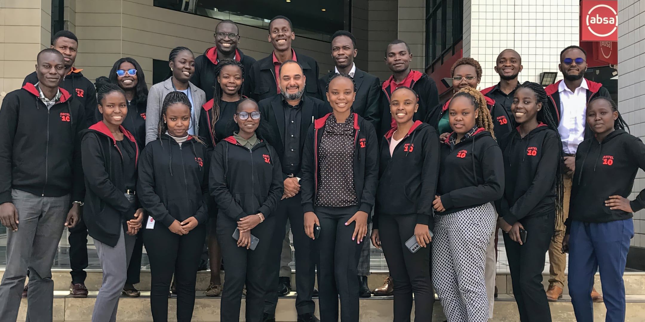 A group of young adults posing in black Airtel-branded sweatshirts