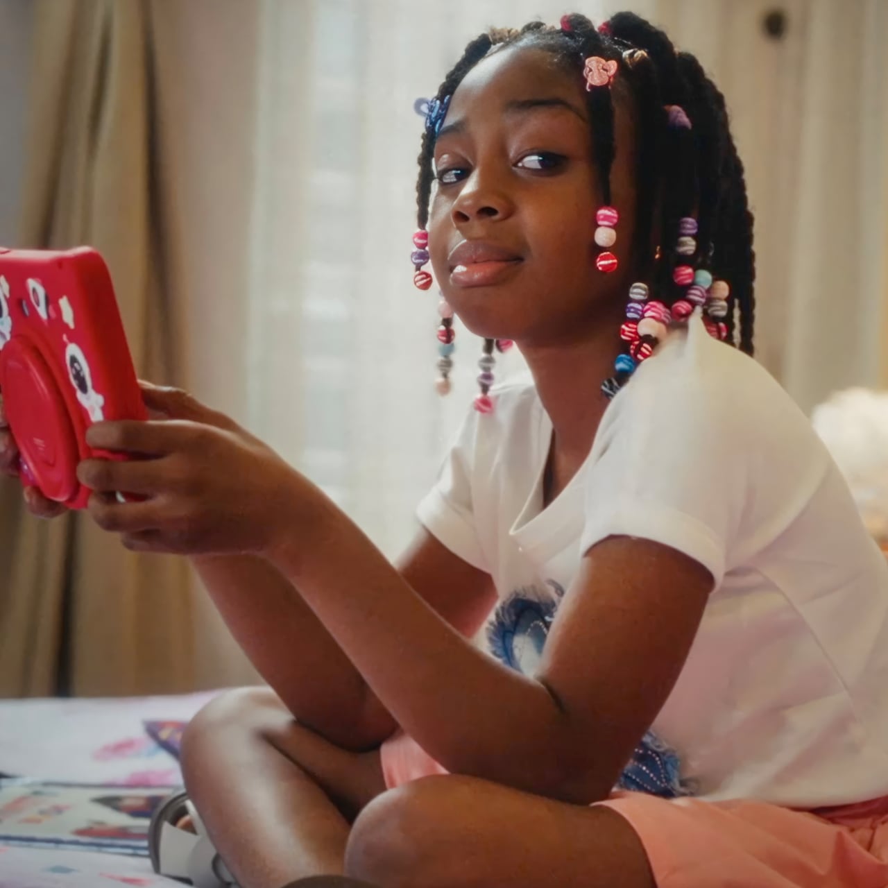 A girl sitting cross-legged with her phone in hand and glancing sideways