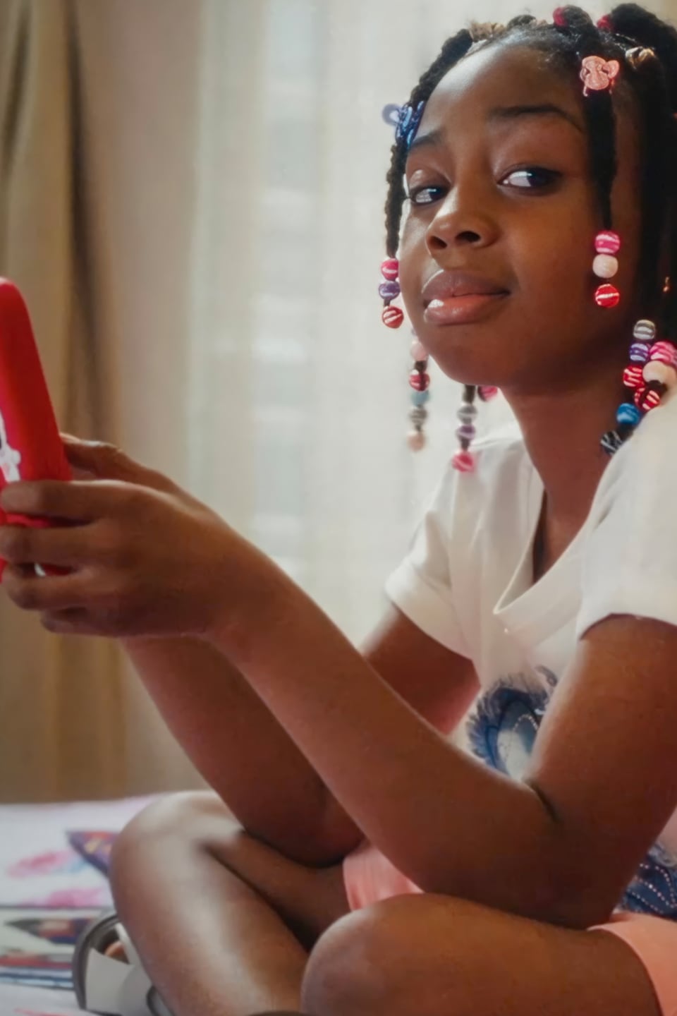A girl sitting cross-legged with her phone in hand and glancing sideways